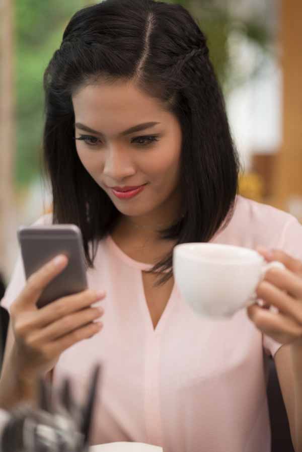 Smiling young woman reading text message 