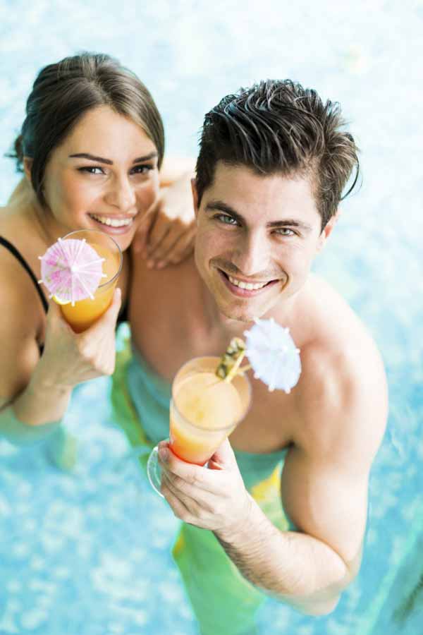 beautiful young couple smiling and drinking a cocktail
