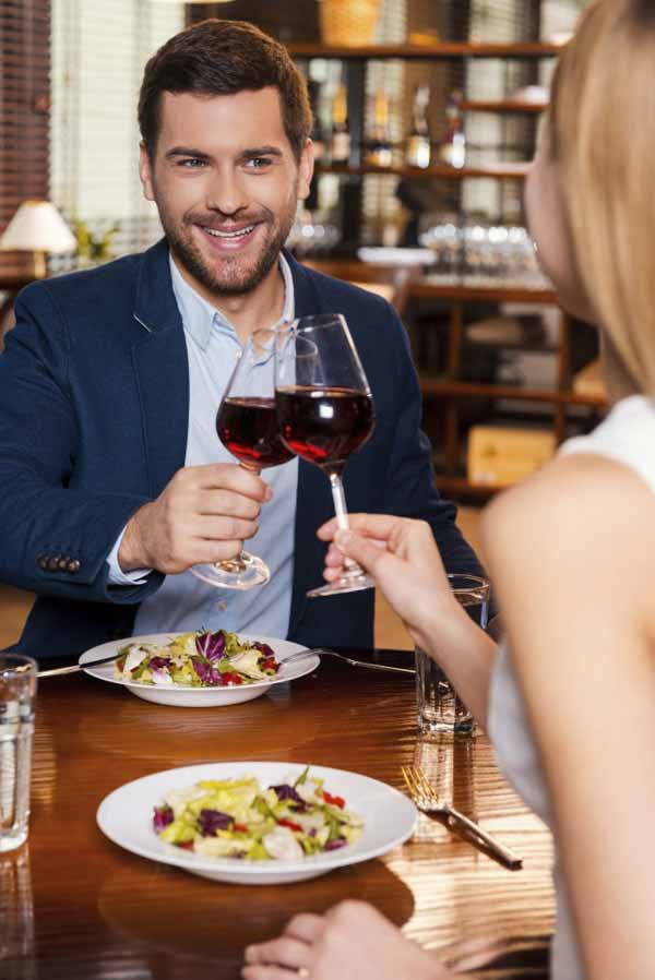Beautiful young loving couple toasting with red wine 